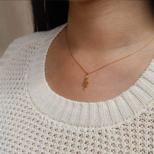 Person wearing a gold snake necklace with a white textured sweater