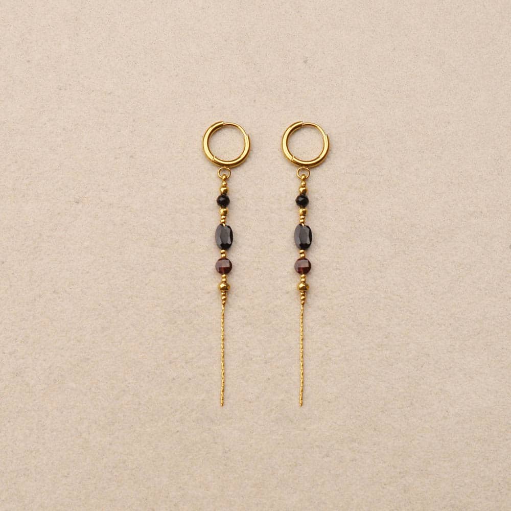 Pair of gold earrings with beads on a beige background