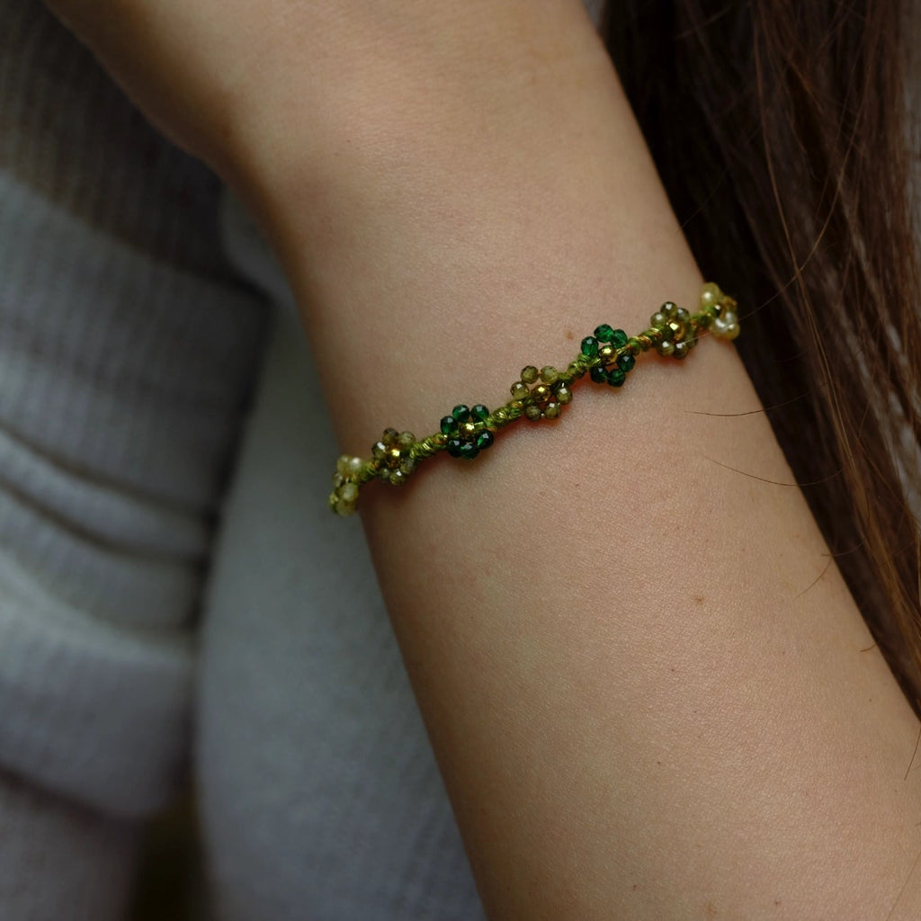 Close-up of a wrist wearing a green beaded bracelet against a neutral background