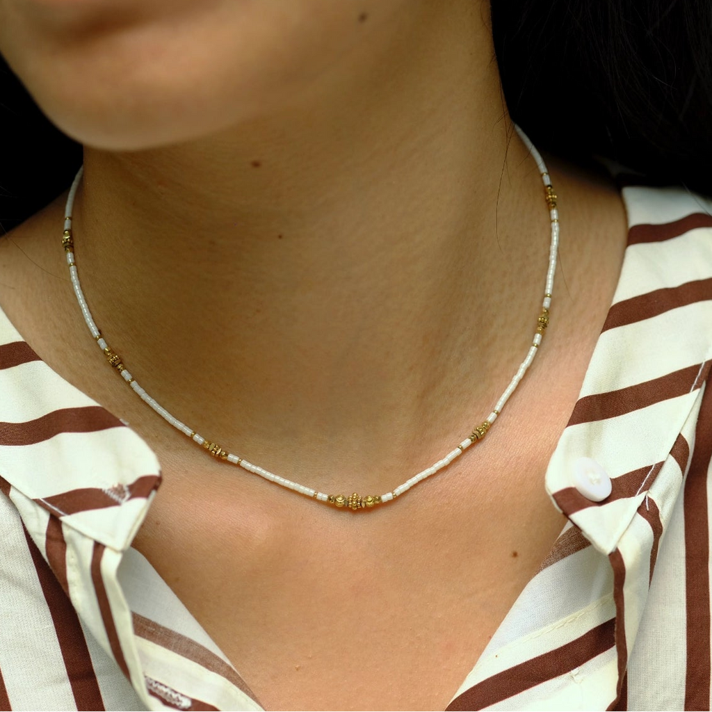 Close-up of a person wearing a gold necklace with a striped shirt.