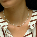 Close-up of a person wearing a gold necklace with a striped shirt.