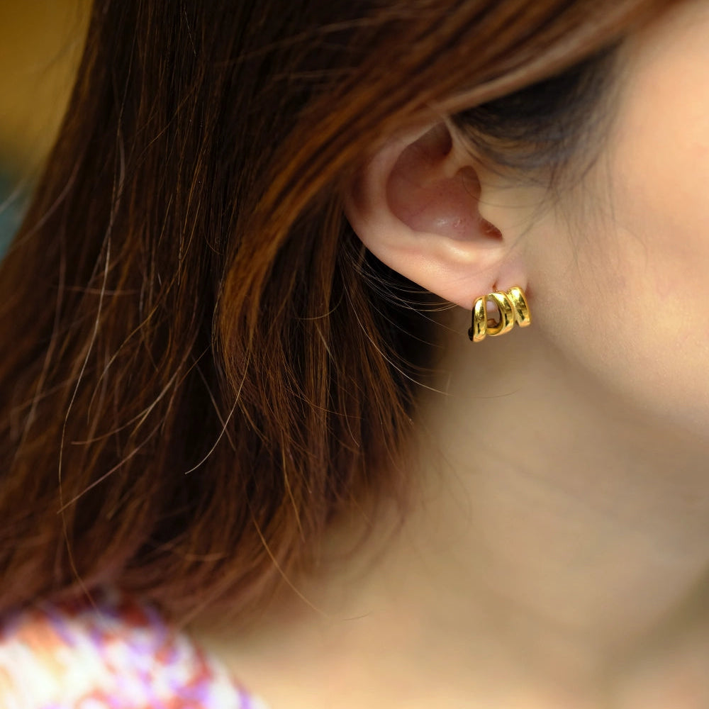 Close-up of a person wearing a gold earring with a blurred background