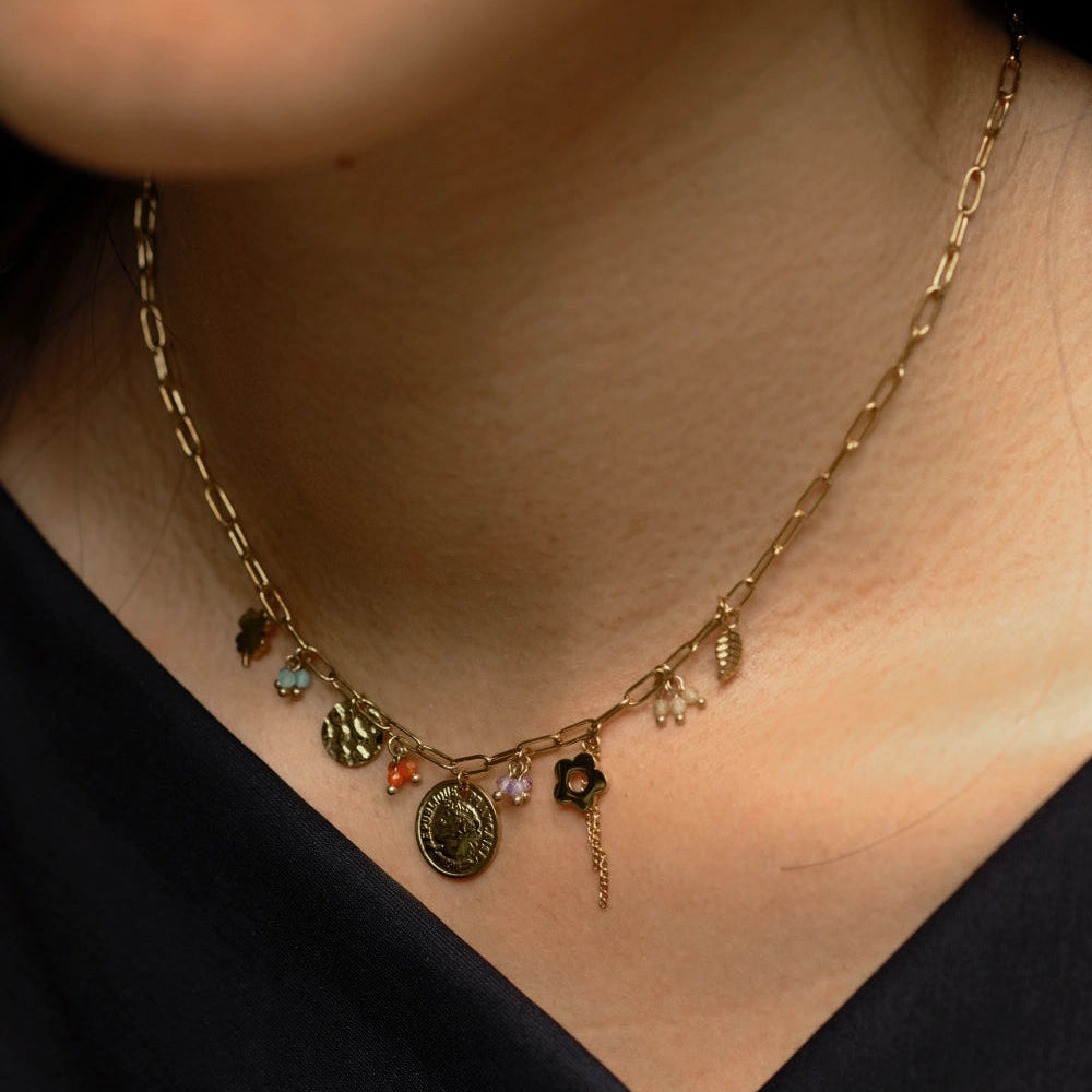 Close-up of a gold necklace with charms on a person wearing a black top.
