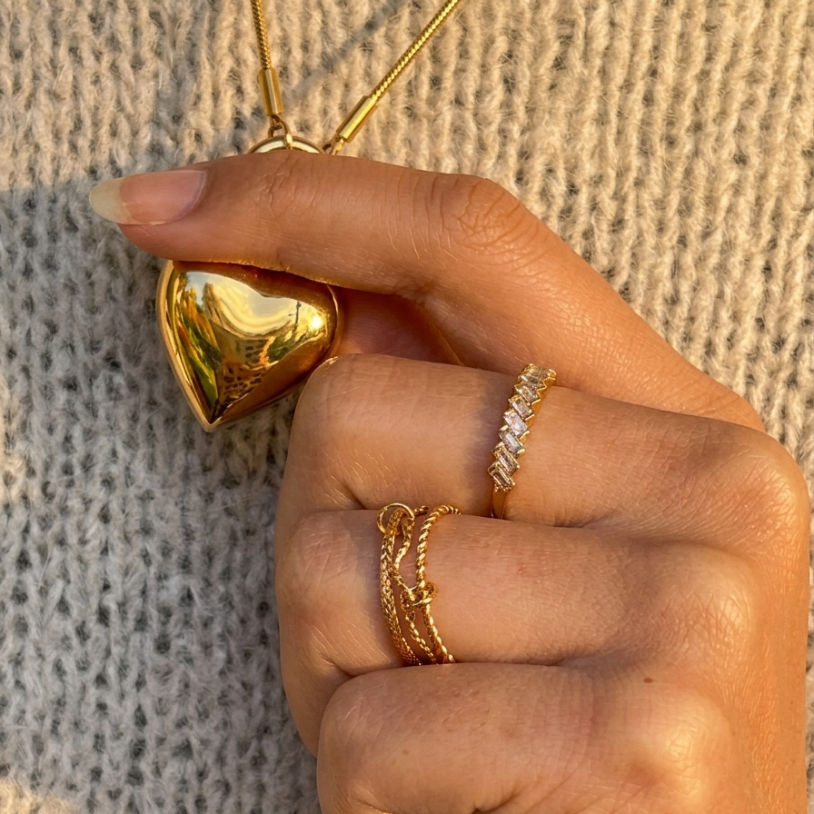 Hand wearing gold rings with a textured background