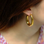 Gold hoop earring worn by a person with a blurred background