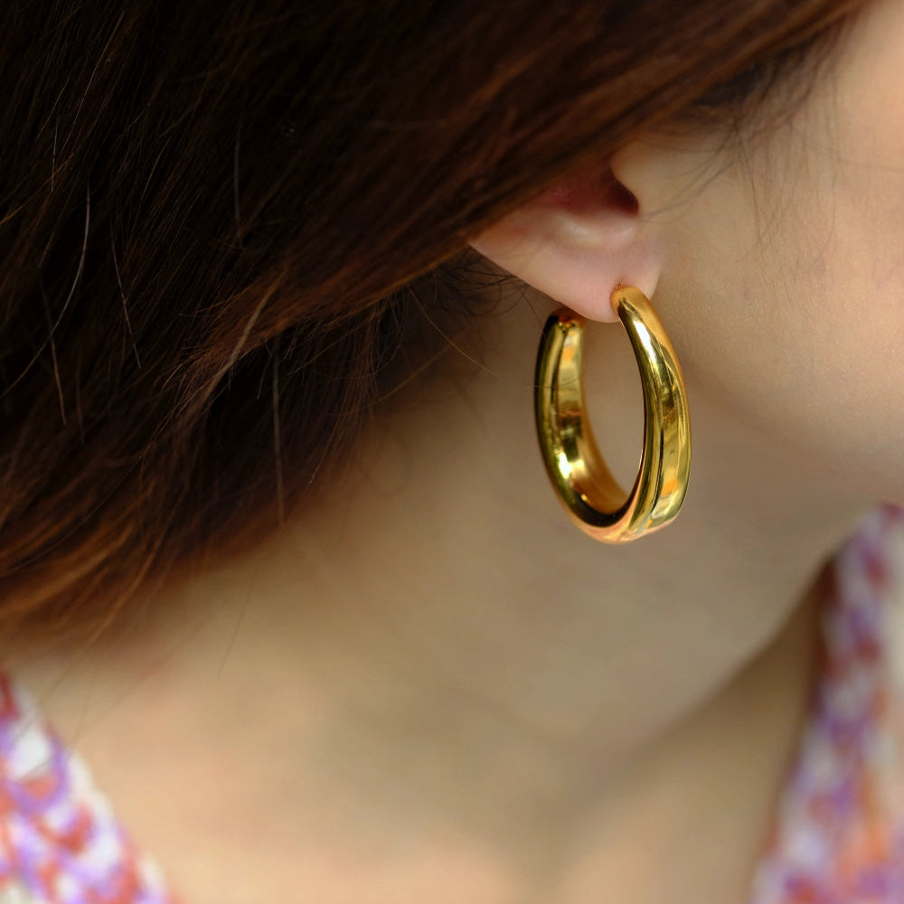 Gold hoop earring worn by a person with a blurred background