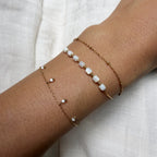 Two pearl anklets on a person's ankle against a light background