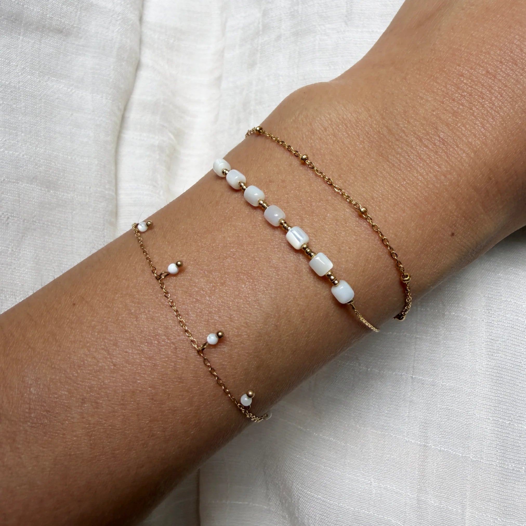 Two pearl anklets on a person's ankle against a light background