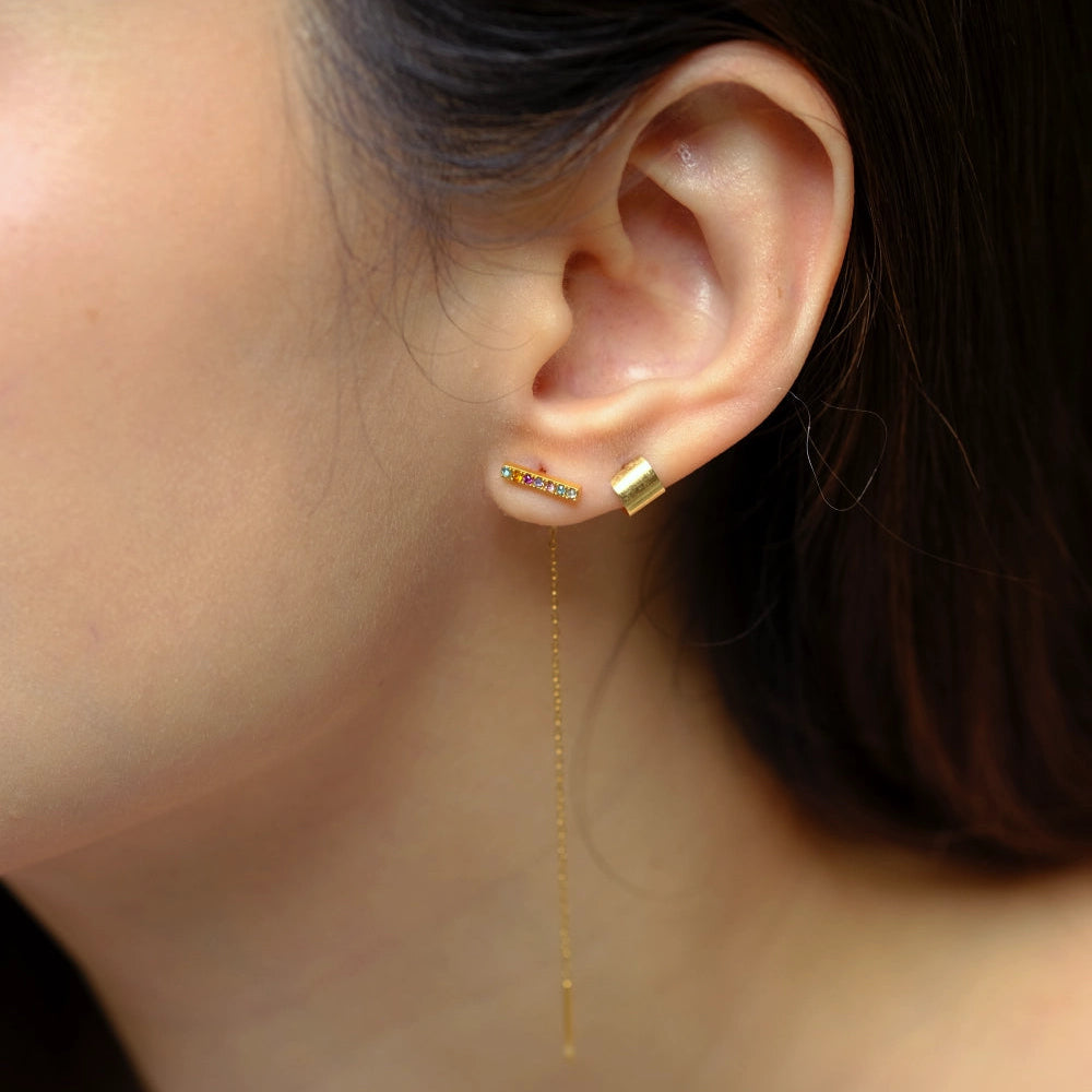 Close-up of an ear wearing a gold earring with a blurred background