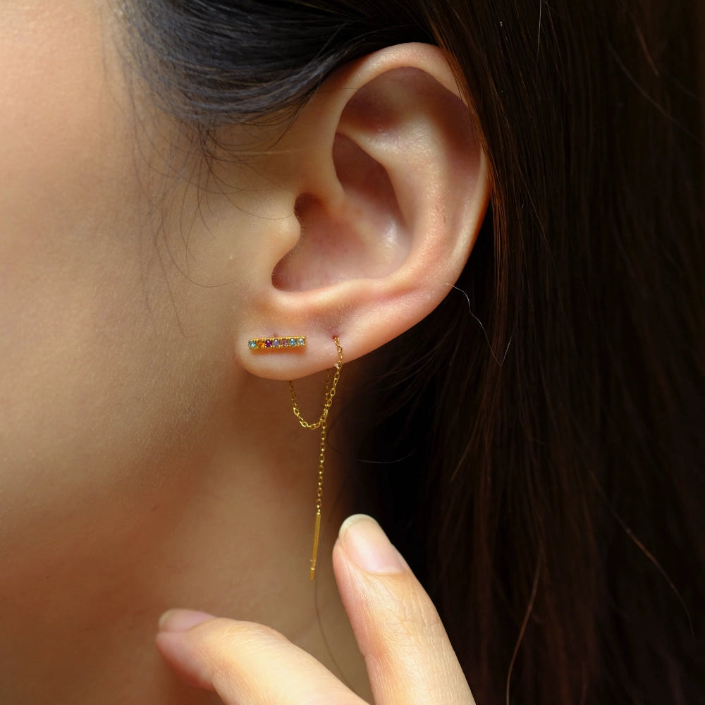 Close-up of an ear wearing a gold earring with a blurred background