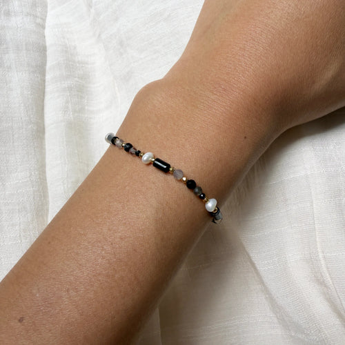 Bracelet with black and white beads on a wrist against a white fabric background