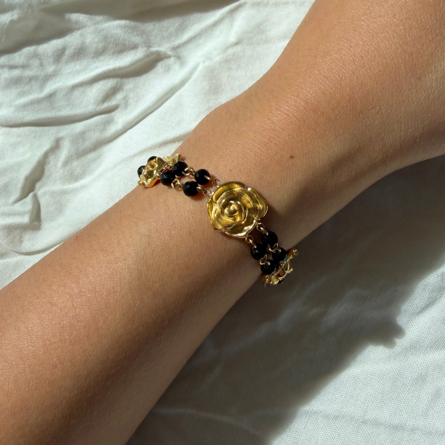 Gold bracelet on a wrist against a white fabric background