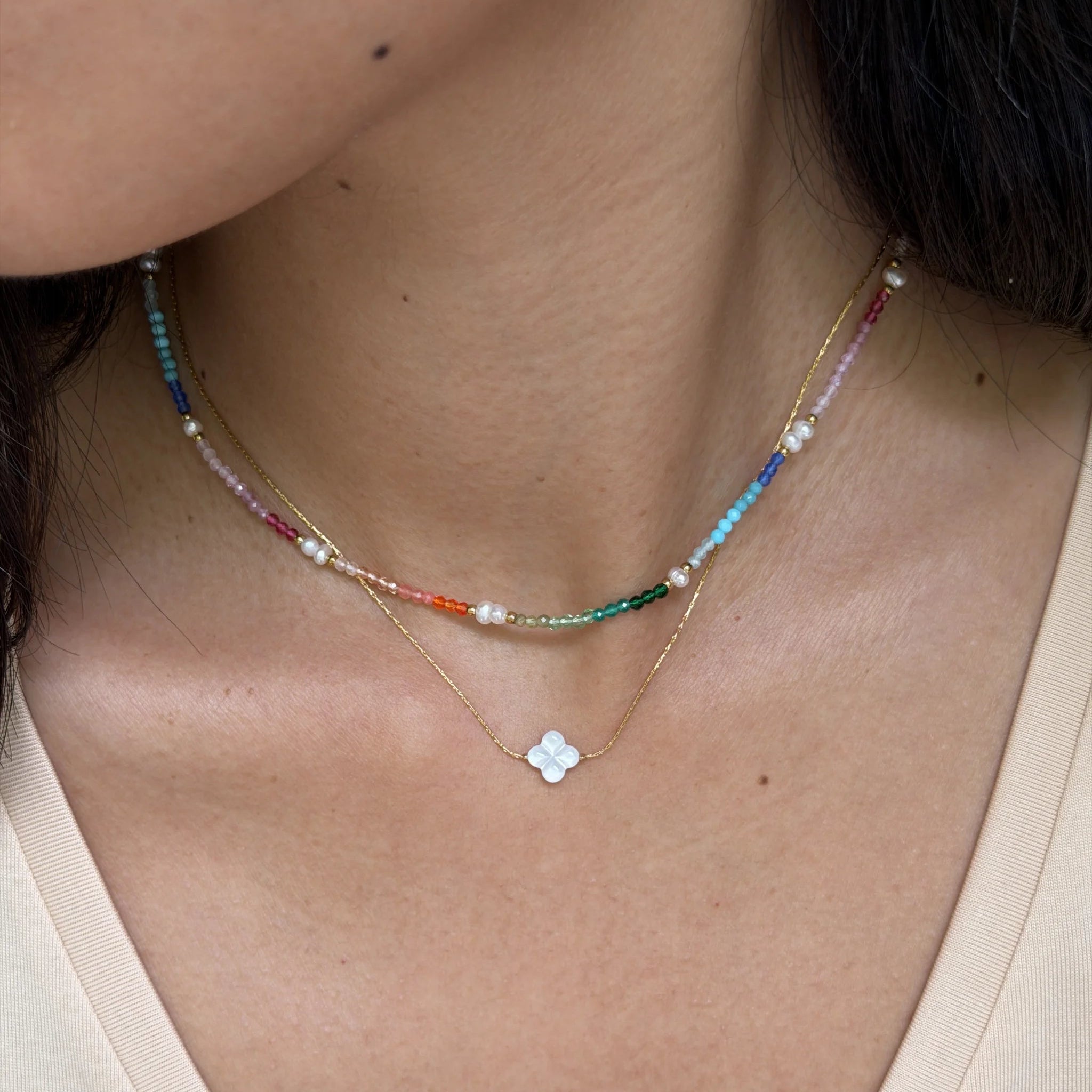 Necklace with a colorful bead and flower pendant worn by a person.