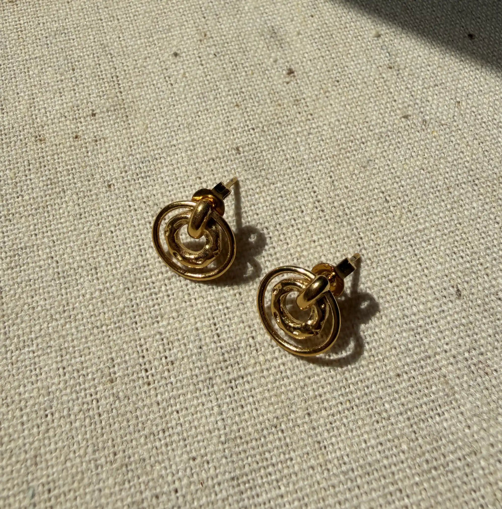 Pair of gold hoop earrings on a textured beige surface