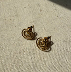 Pair of gold hoop earrings on a textured beige surface