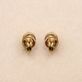 Pair of gold knot earrings on a beige background
