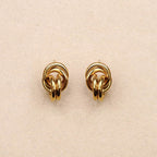 Pair of gold knot earrings on a beige background