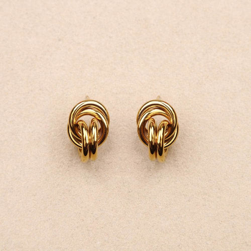Pair of gold knot earrings on a beige background