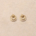 Pair of gold earrings on a beige fabric background