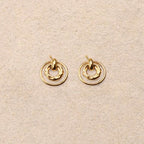 Pair of gold earrings on a beige fabric background