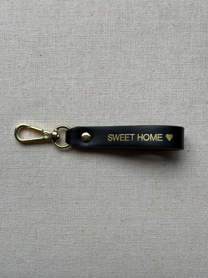 Stylish black leather keychain with leash, with "Sweet Home" printed on it