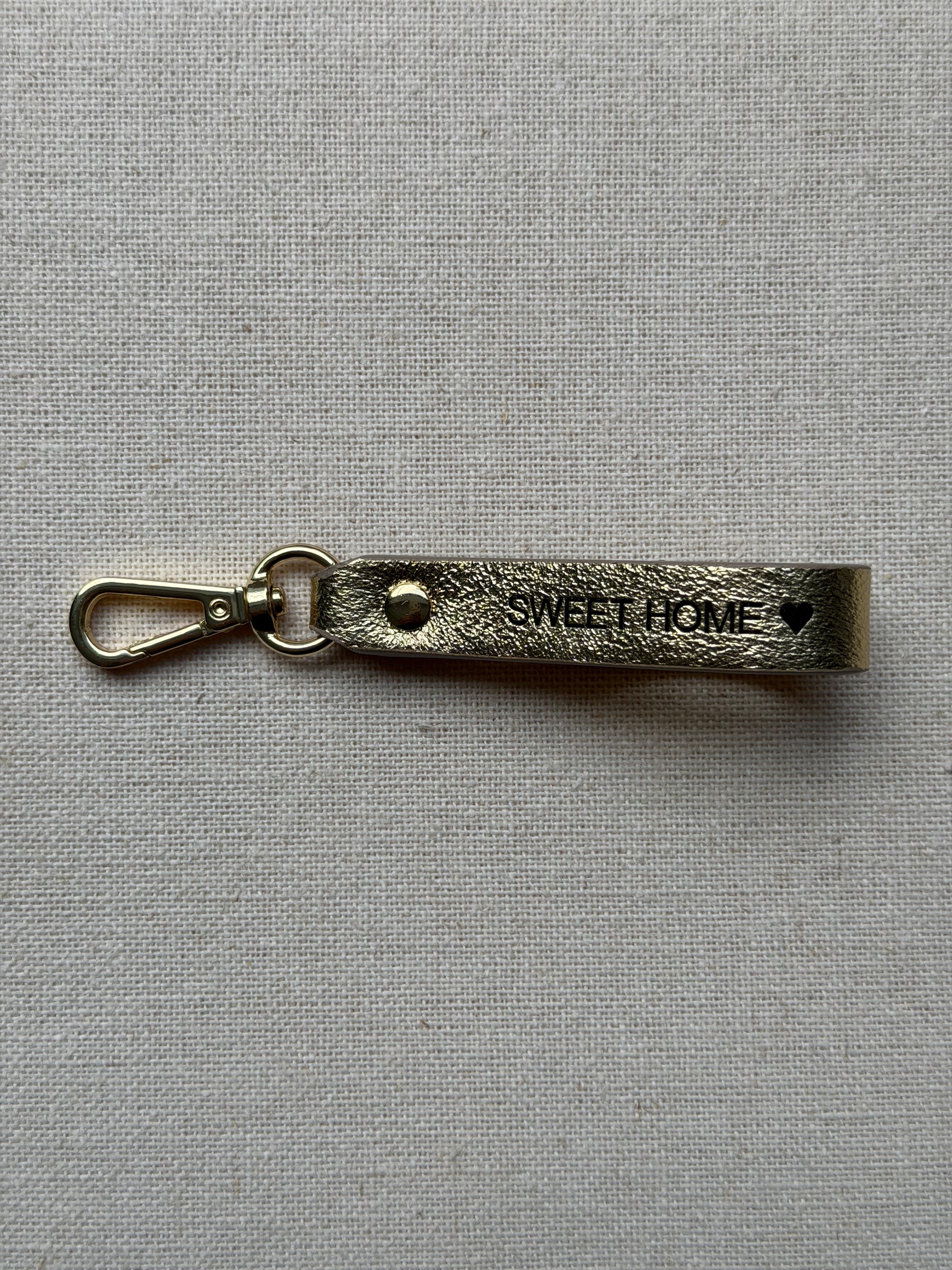 Stylish gold leather keychain with leash, with "Sweet Home" printed on it