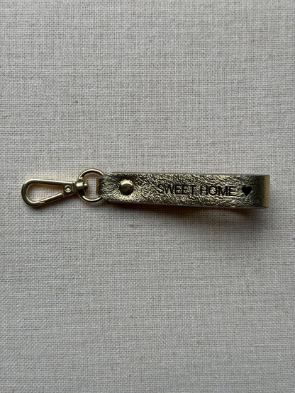 Stylish gold leather keychain with leash, with "Sweet Home" printed on it