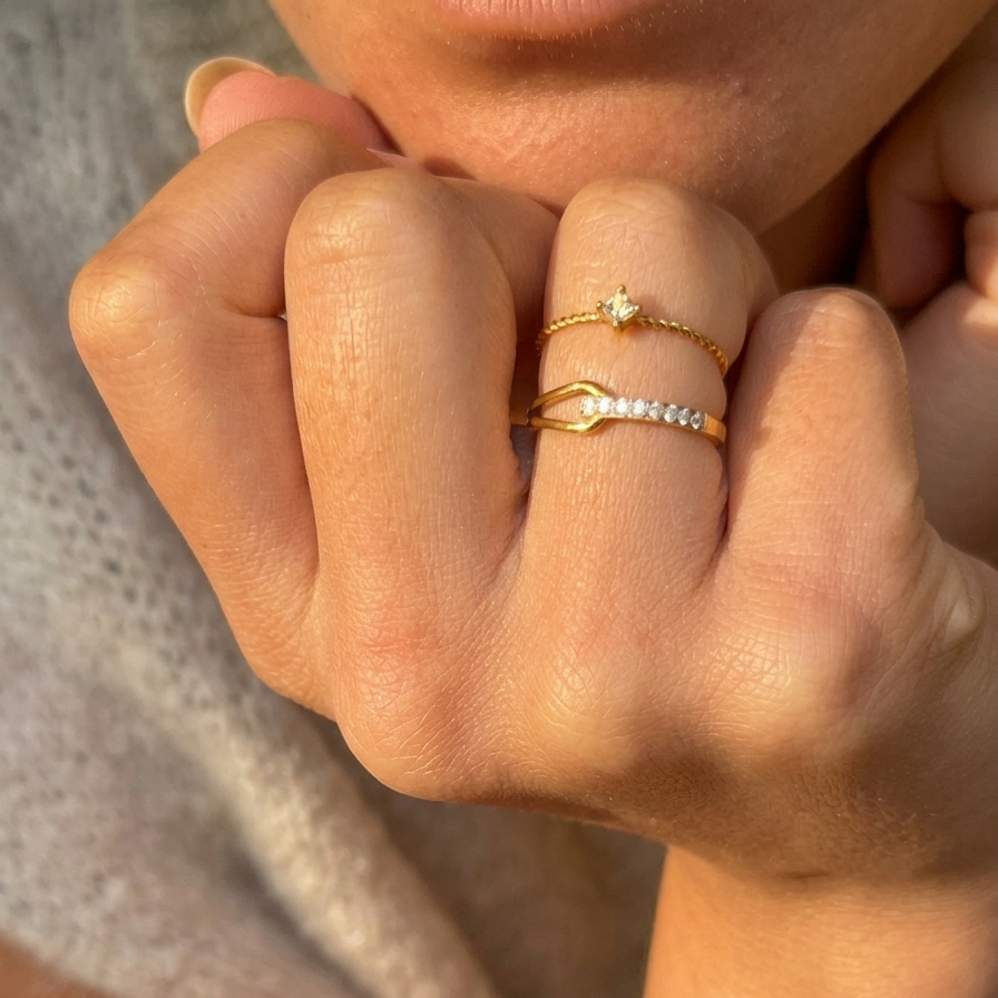 Close-up of a hand wearing gold rings with a soft background