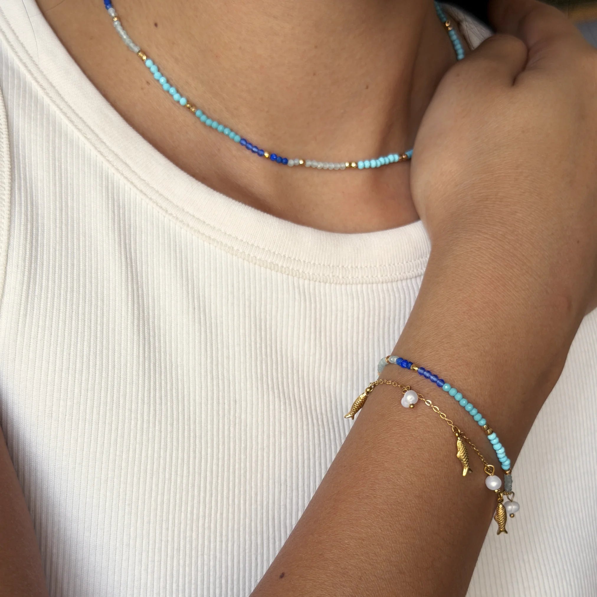 Necklace and bracelet with blue and gold beads on a white background