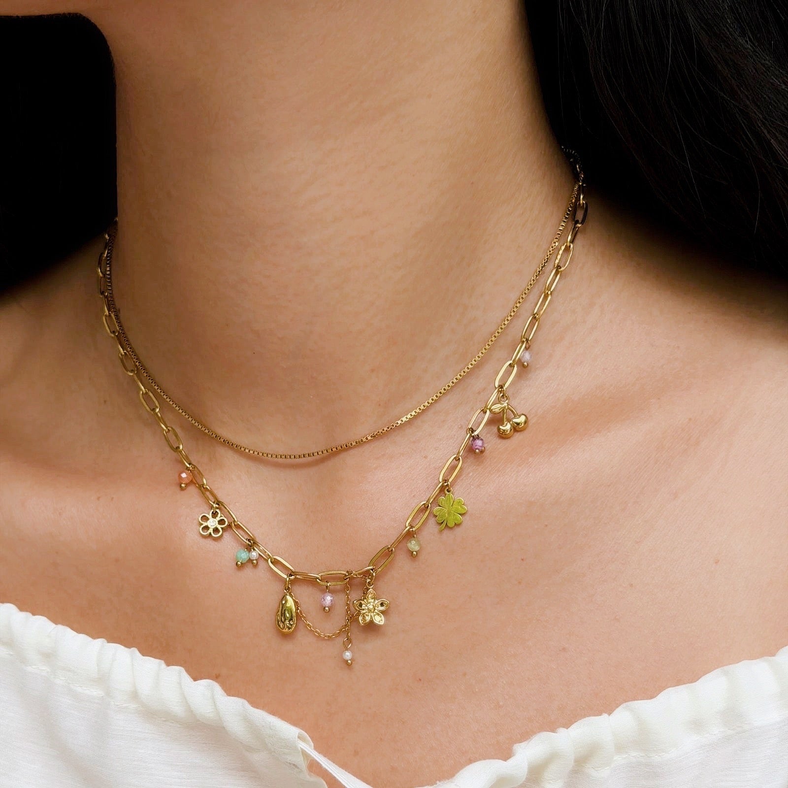 Les Cleias Double-row necklace with floral charms on a person wearing a white top.