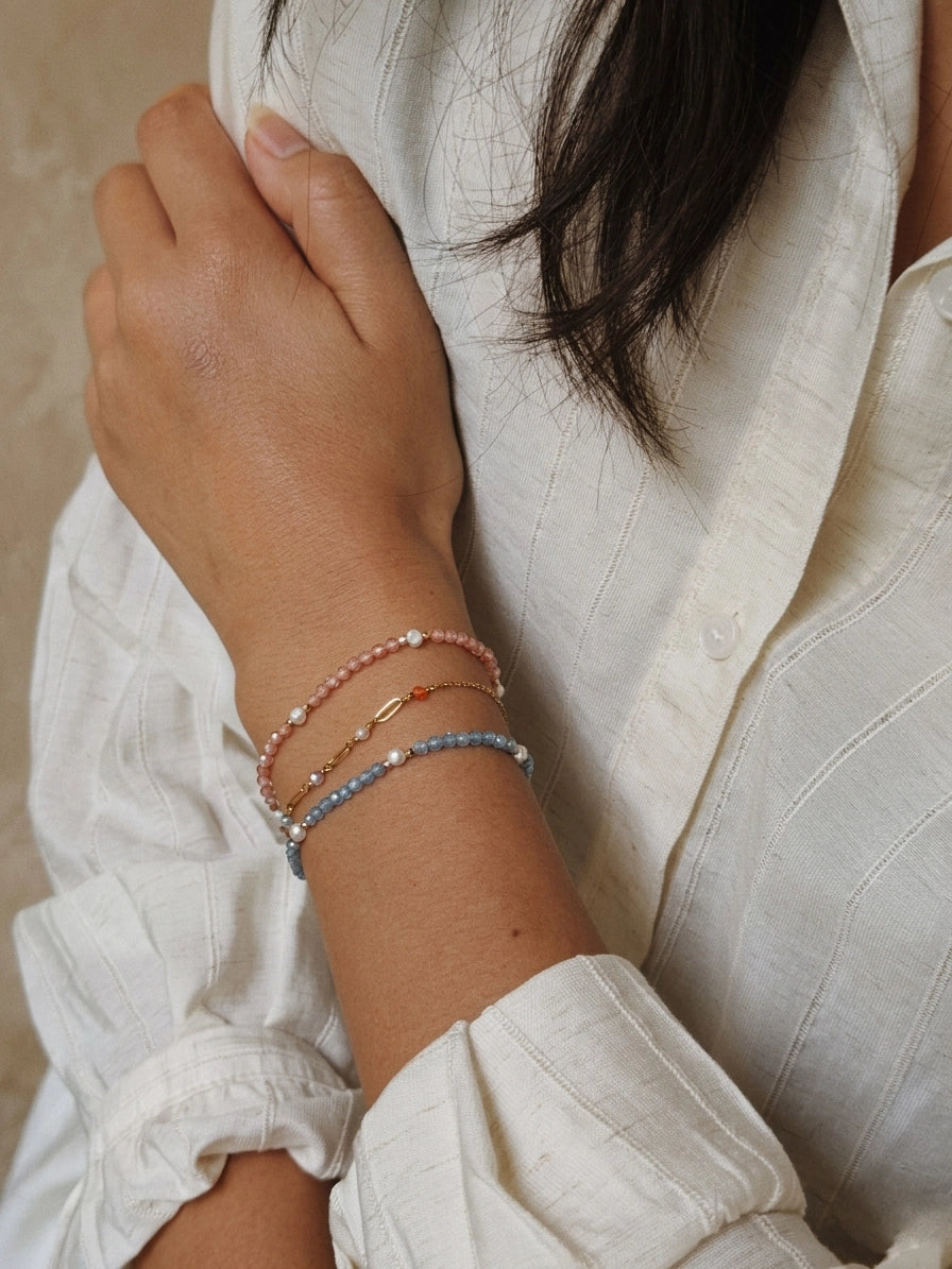 Close-up of a person wearing multiple bracelets on a white background