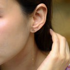 Close-up of a person wearing gold earrings with a blurred background