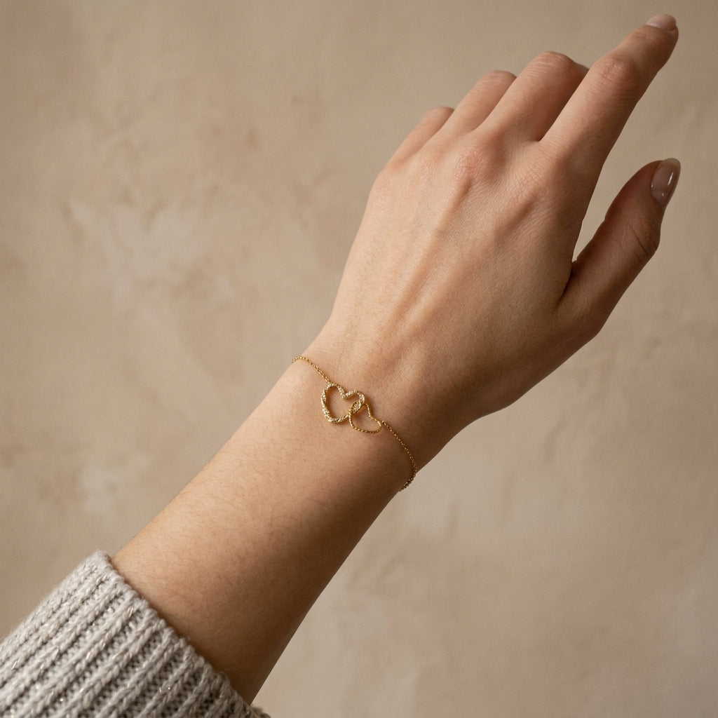 Hand wearing a gold bracelet on a beige background