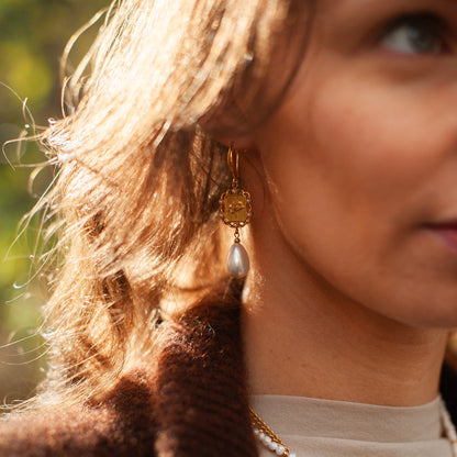 Close-up of a woman wearing gold earrings and a necklace with a blurred background