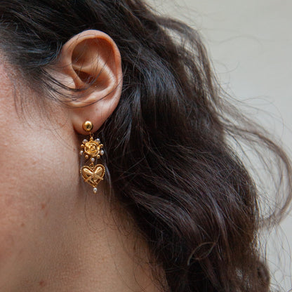 Close-up of a person wearing gold earrings with a neutral background
