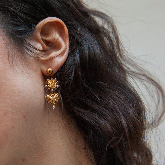 Close-up of a person wearing gold earrings with a neutral background