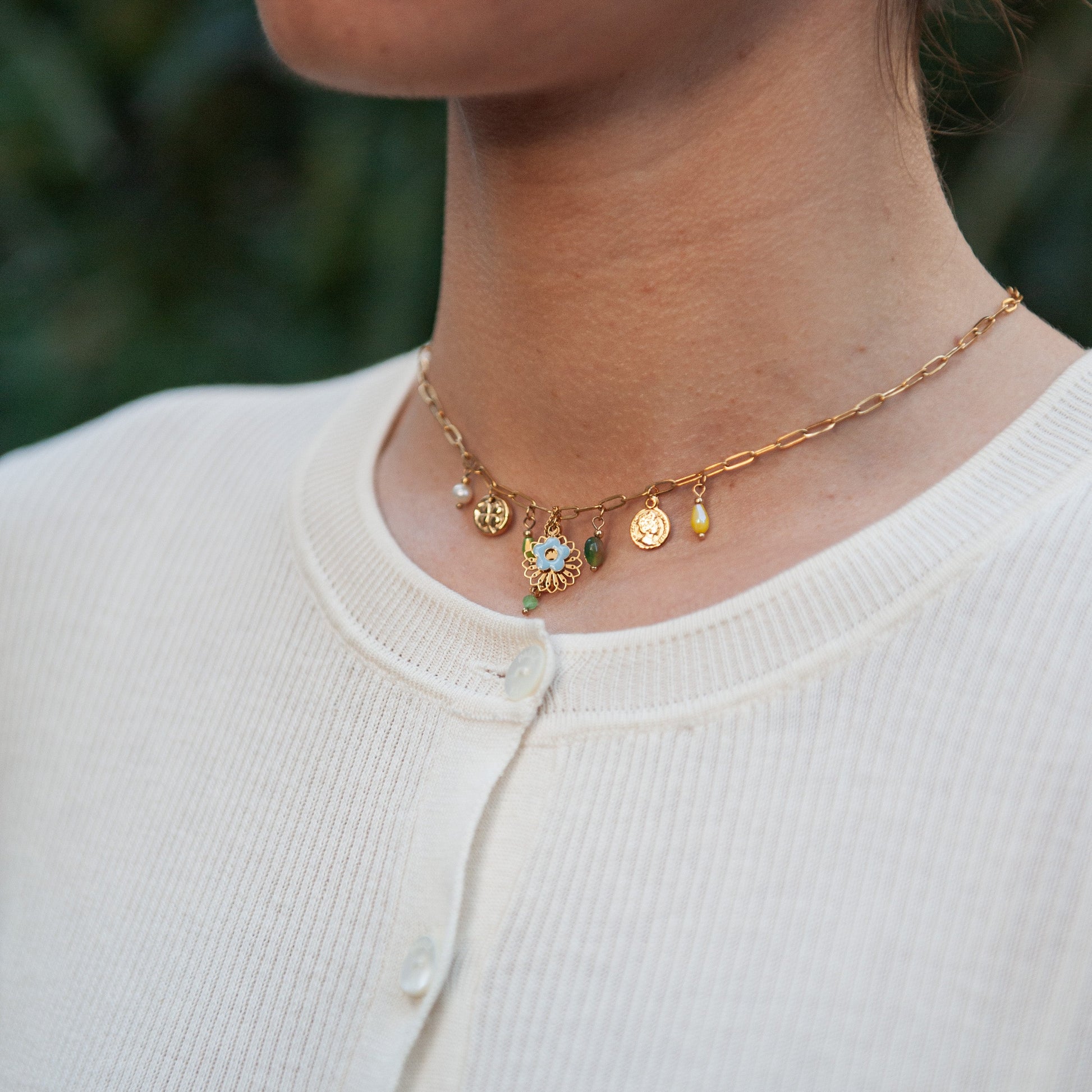 Necklace with charms worn by a person against a blurred green background