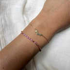 Two delicate bracelets on a wrist against a white background