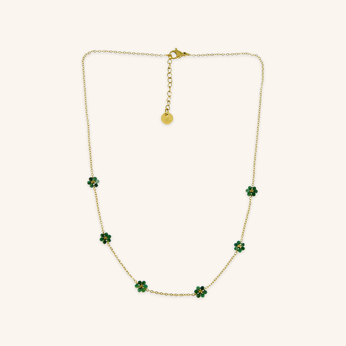 A person wearing a stainless steel necklace with gold plating and small white gemstones, paired with a matching bracelet.