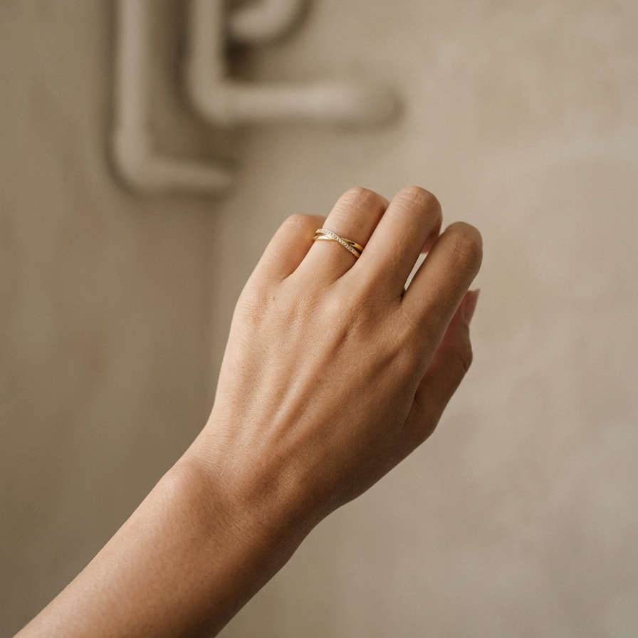 Hand wearing a gold ring on a neutral background