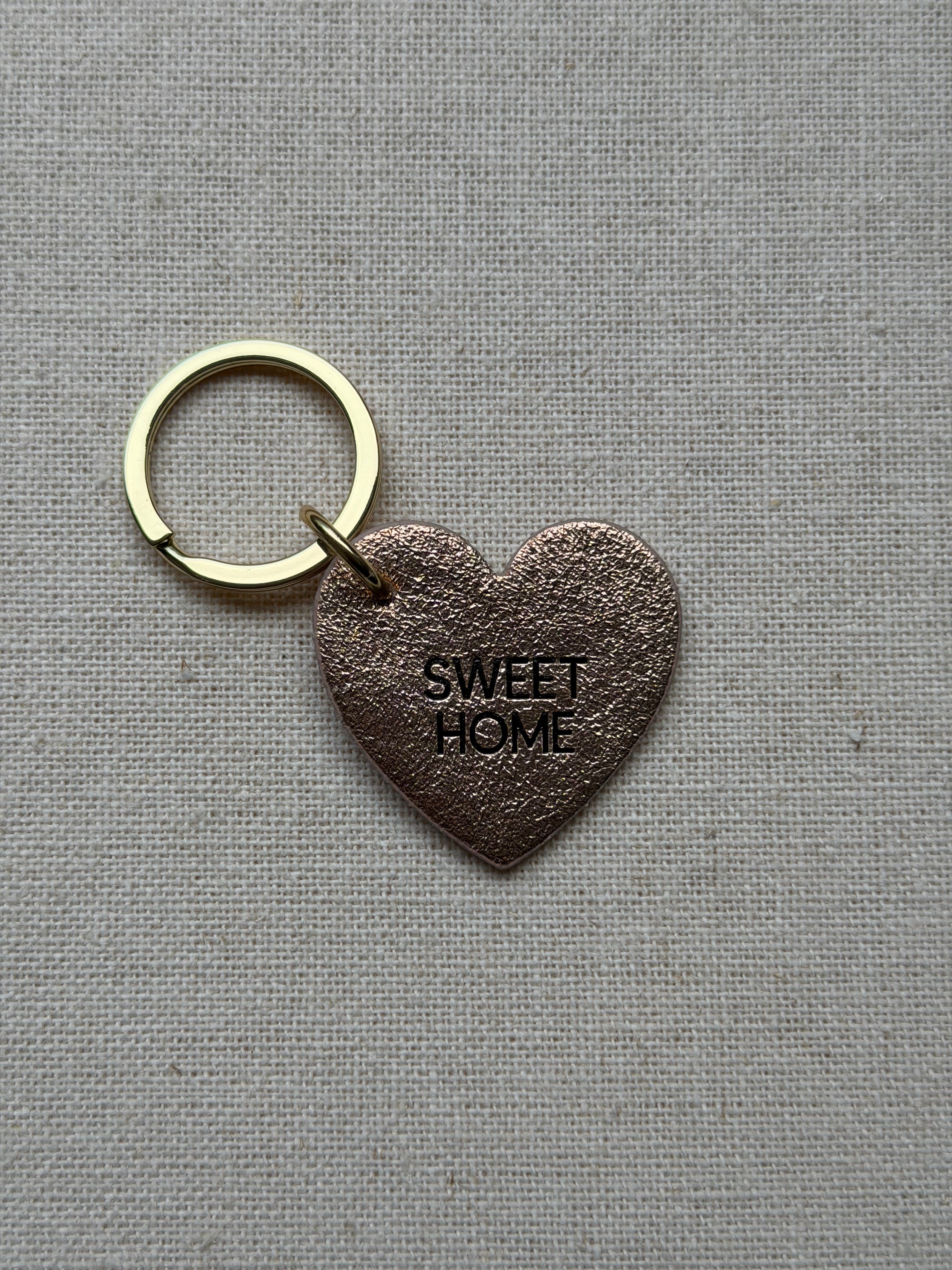 heart shaped iridescent leather keychain with sweet home printed on it
