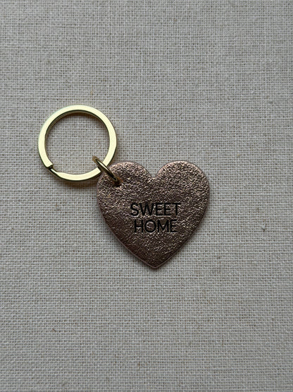 heart shaped iridescent leather keychain with sweet home printed on it