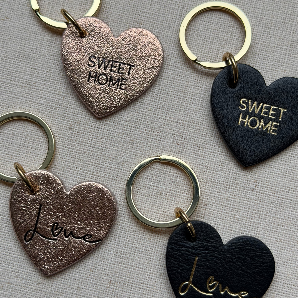 Heart-shaped keychains with 'Sweet Home' and 'Love' text on a textured surface