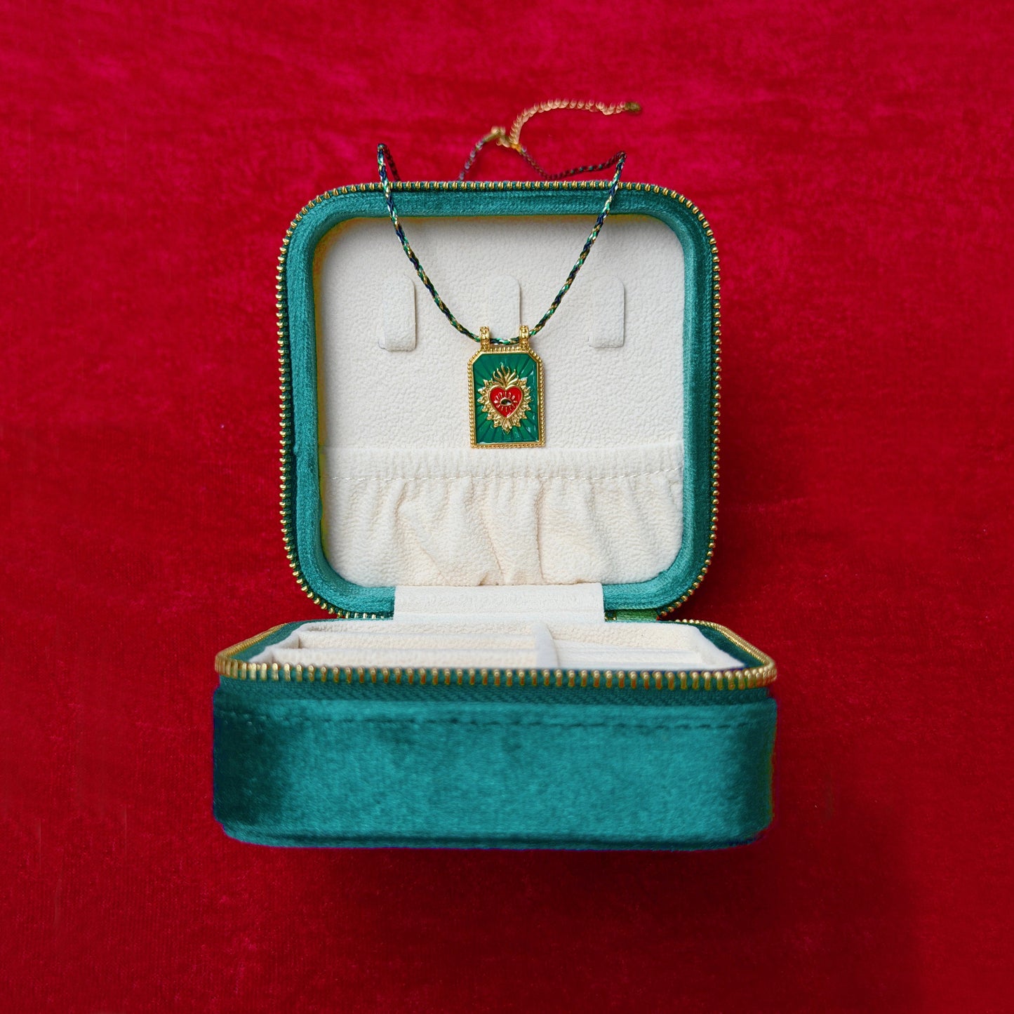 Teal jewelry box with a necklace featuring a heart pendant on a red background