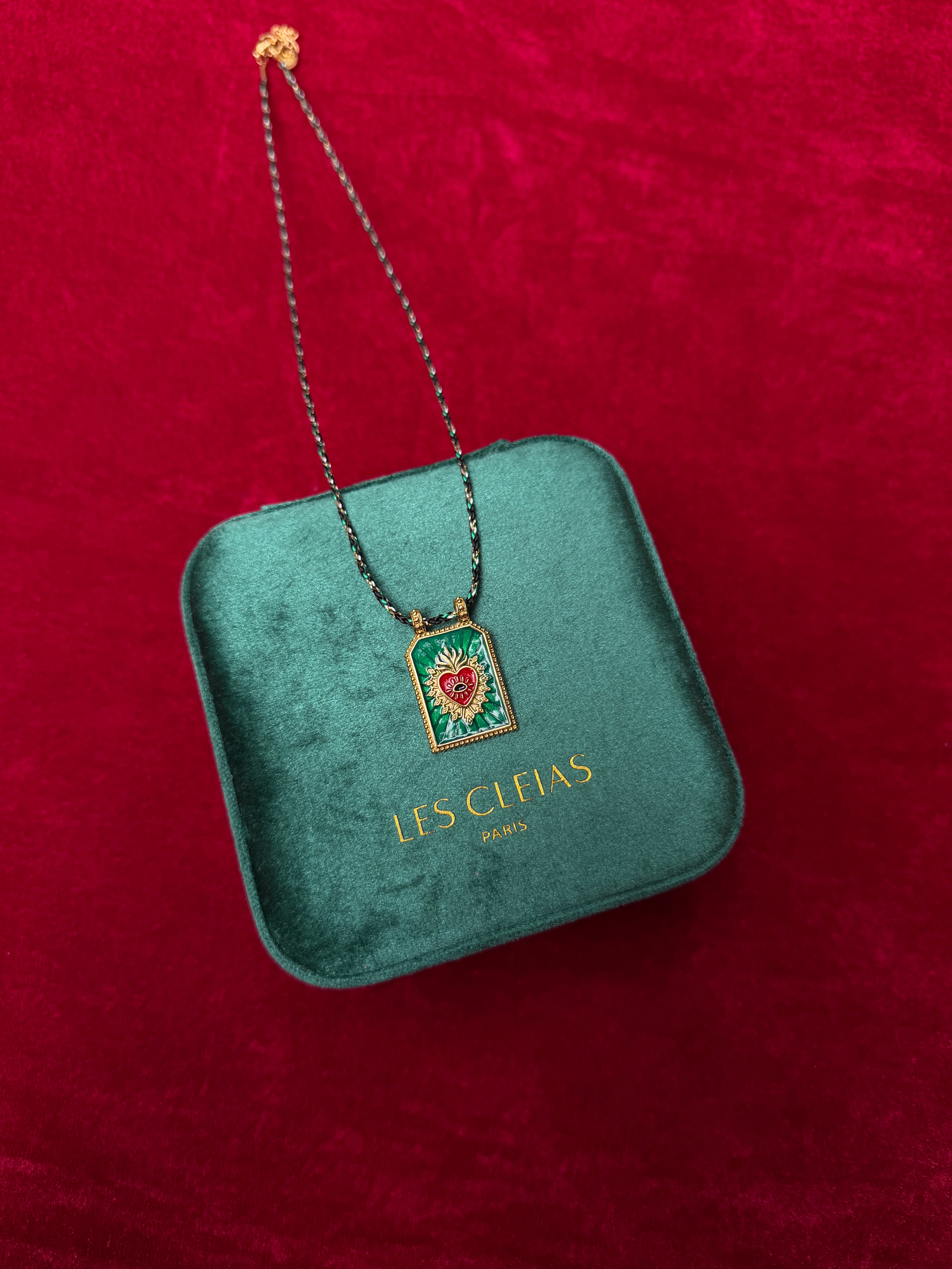 Necklace with a pendant on a green jewelry box against a red background