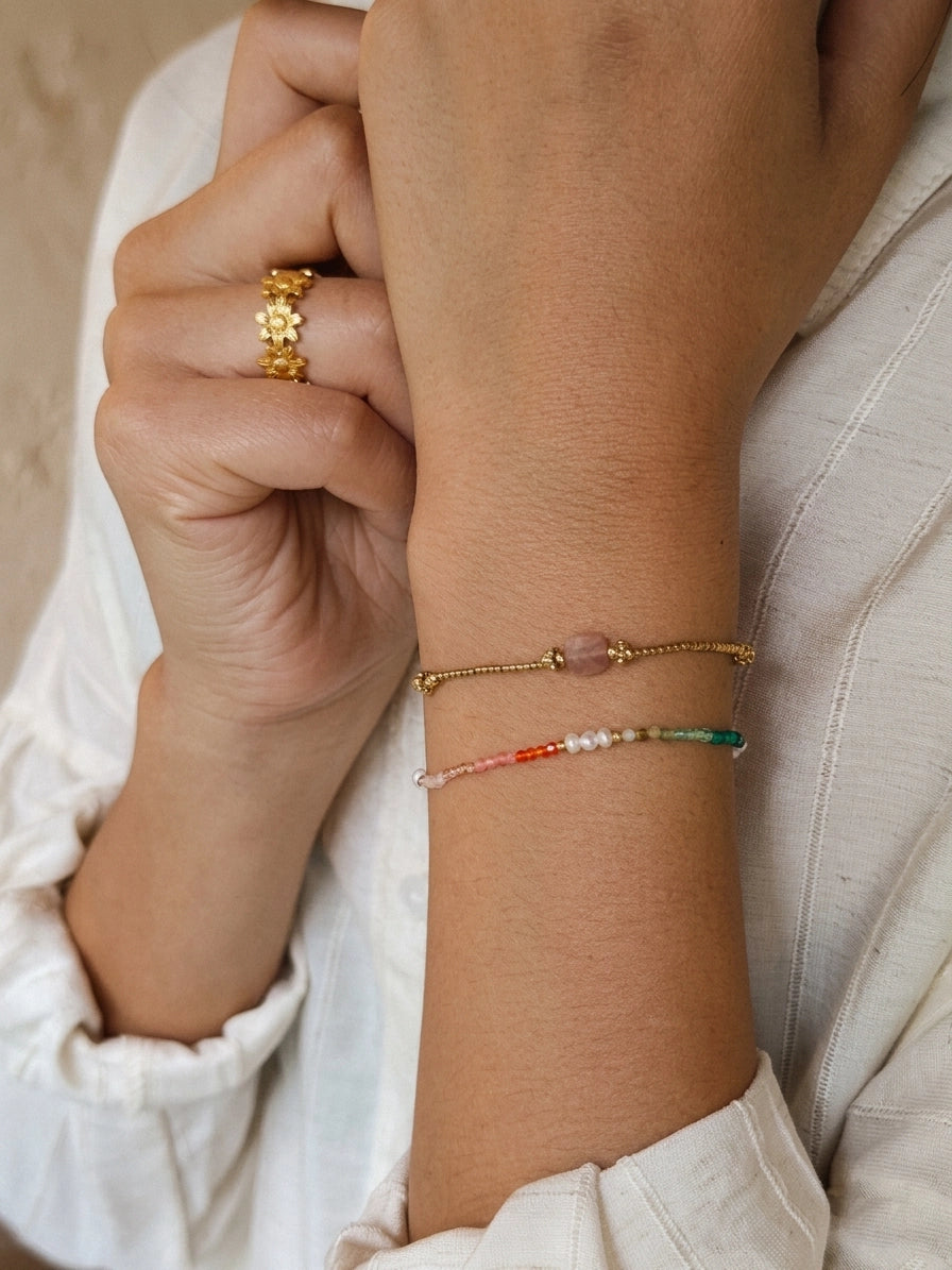 Close-up of a wrist wearing gold bracelets with colorful beads.