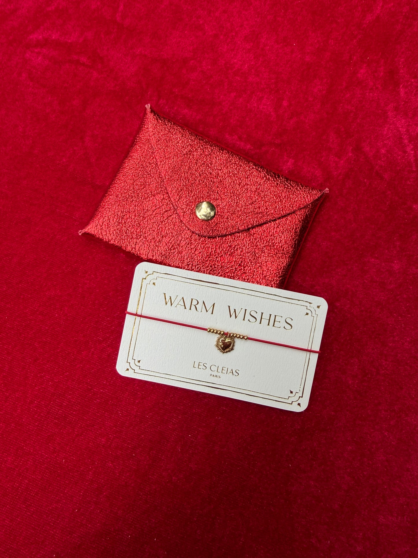Red leather cardholder with a 'Warm Wishes' card on a red background