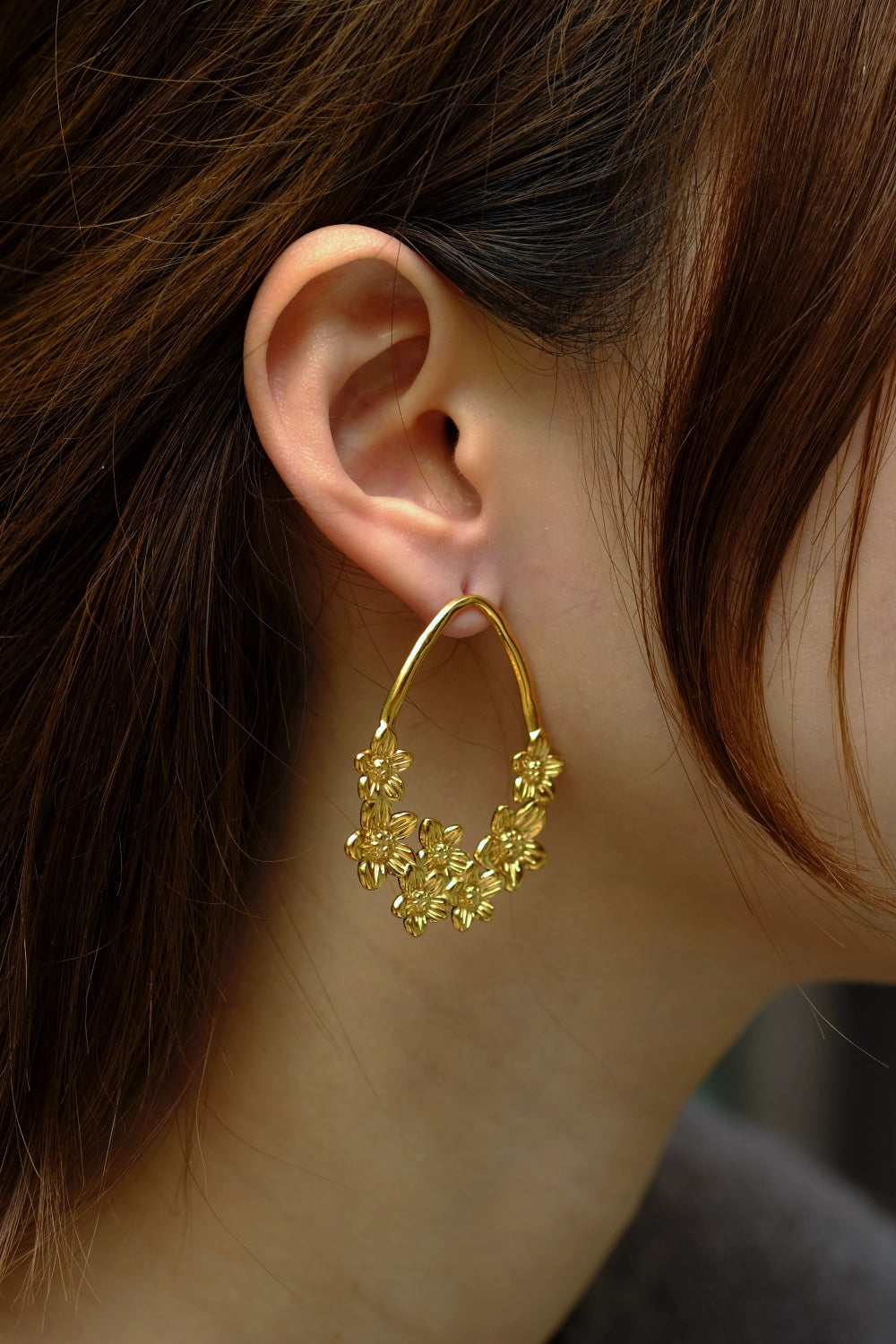Gold hoop earring worn by a person with brown hair.