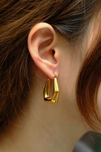 Gold hoop earring worn by a person with brown hair.