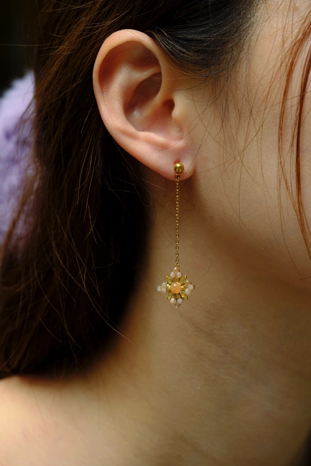 Close-up of a person wearing a gold earring with a star-shaped pendant.